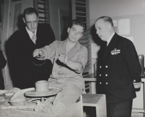 A war veteran talking to Admiral Monroe Kelly (right) about his pottery work.