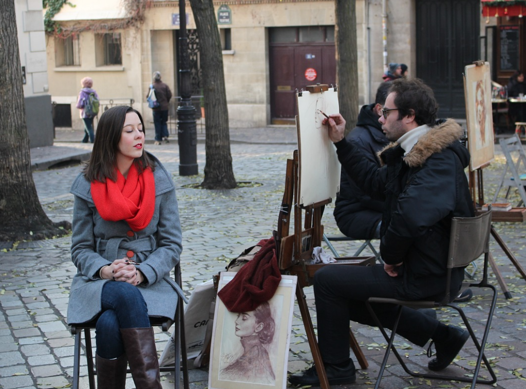 An artist paints a portrait for a tourist in modern-day Montmartre. Photo by stinne24. 