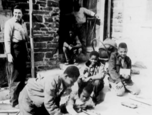 Kramer (left) overseeing student’s work at the Little Red School House circa 1939. Via YouTube. 